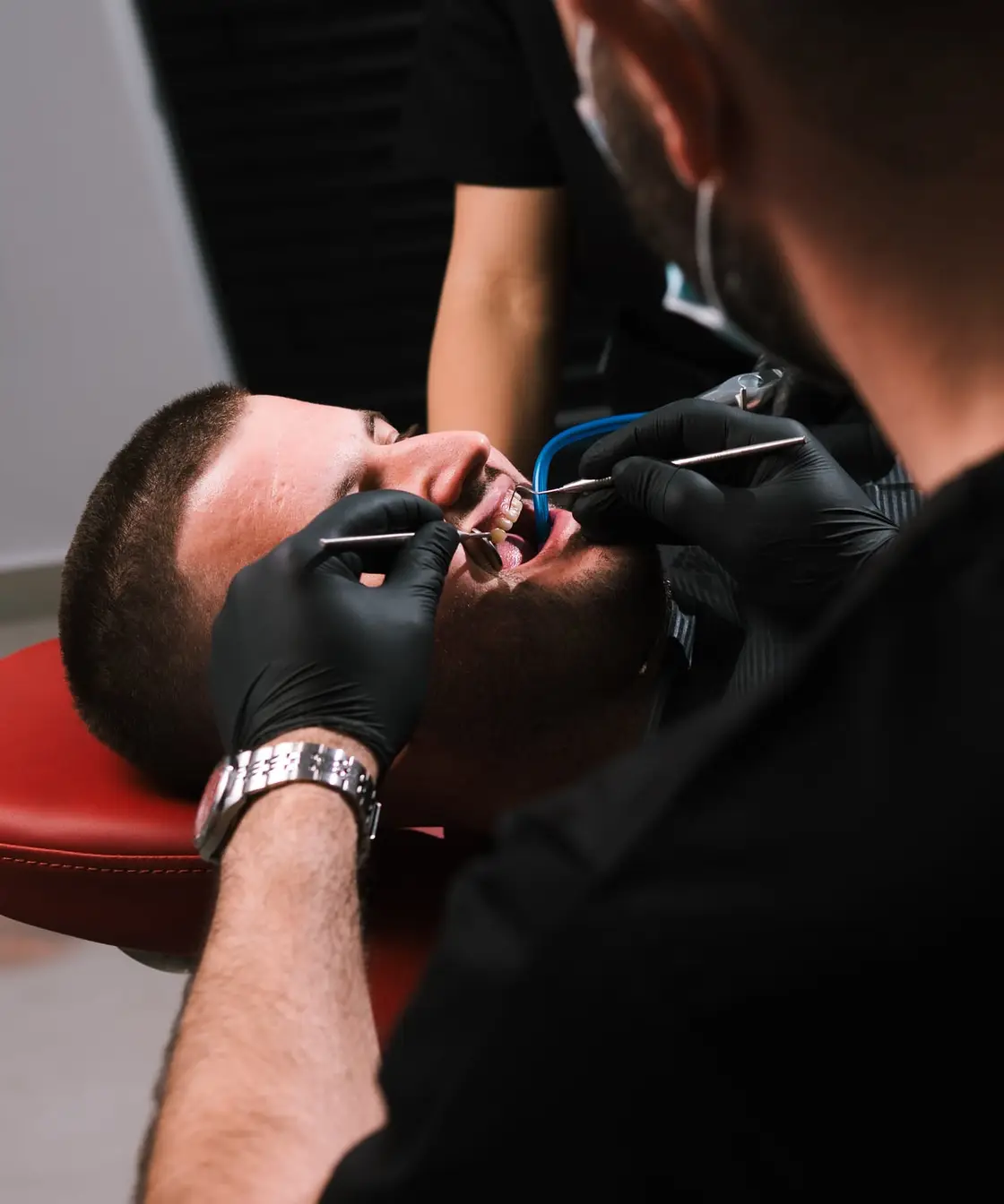 Dr Agron Shabani examining a patient’s teeth with a dental mirror and probe